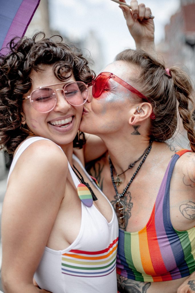 Two women smiling and kissing at a pride event. Representing lgbtq counseling.