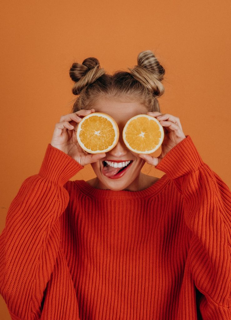 woman holding two slices of orange