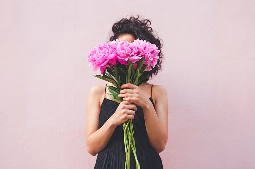 woman covering her face with purple flowers