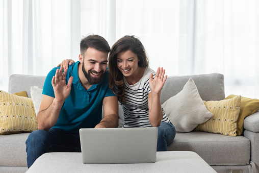 couple greeting someone on their laptop