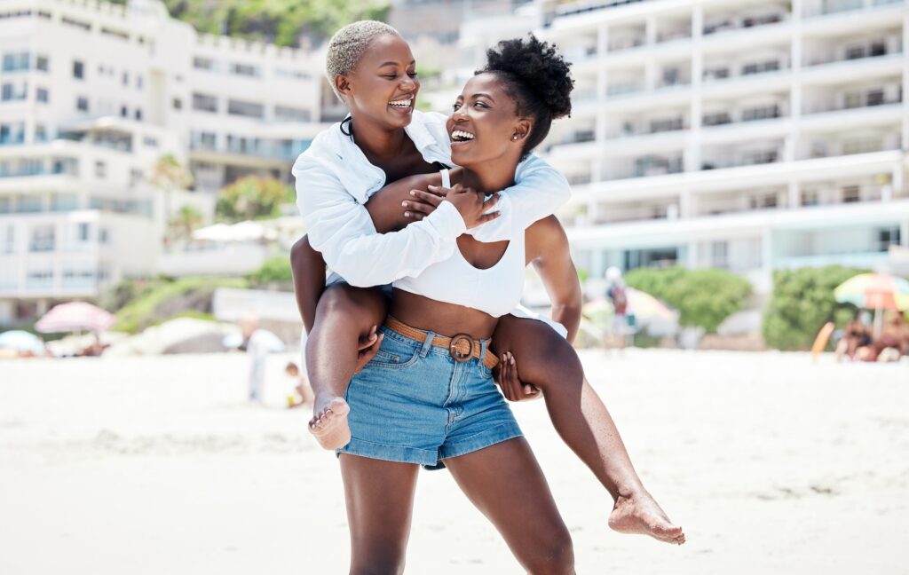 lesbian gay and lgbt with a woman couple having fun with a smile together on the beach during summ