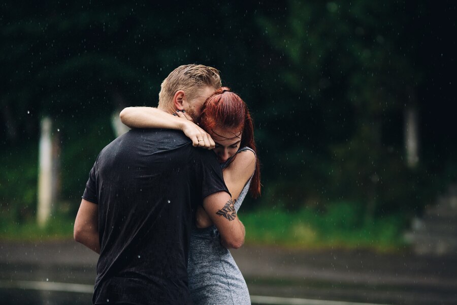 Intimate couple hugging outside while raining
